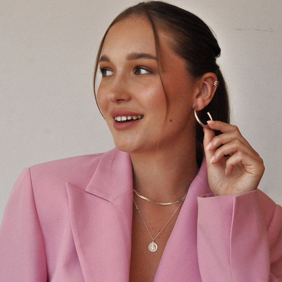 Smiling woman wearing Gioia 925 sterling silver layered necklace set with pink blazer