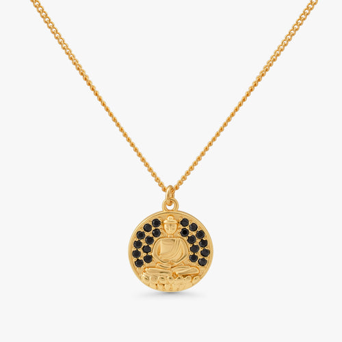 A gold pendant necklace featuring a circular medallion with a seated Buddha figure, accented by small black stones around the upper half, suspended from a delicate gold chain against a light gray background.