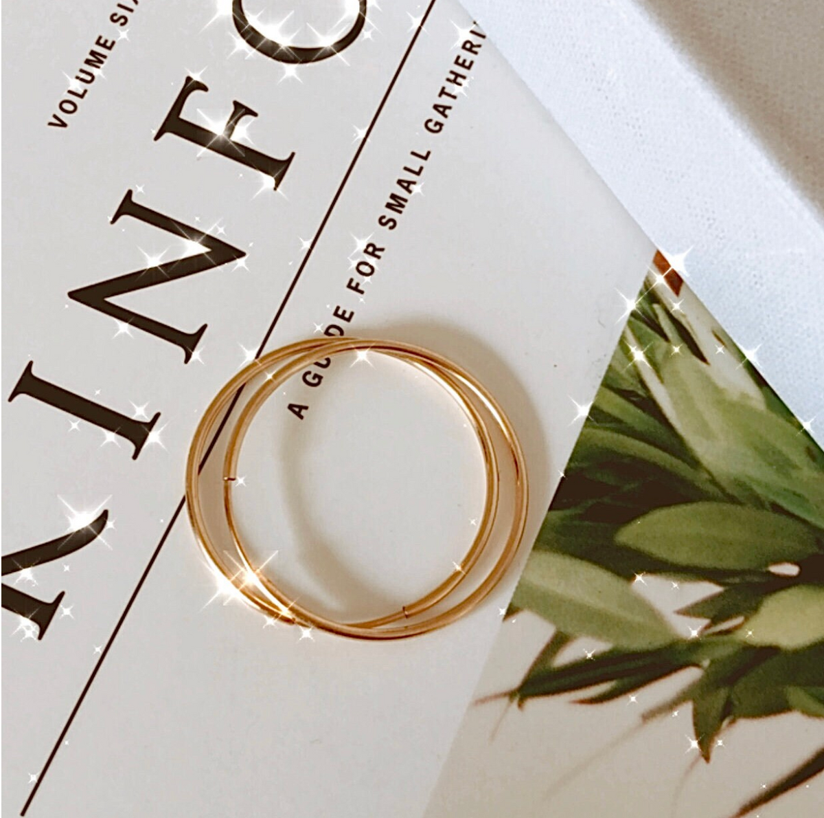 14k gold filled Nia sleeper hoop earring displayed on magazine with green leaves