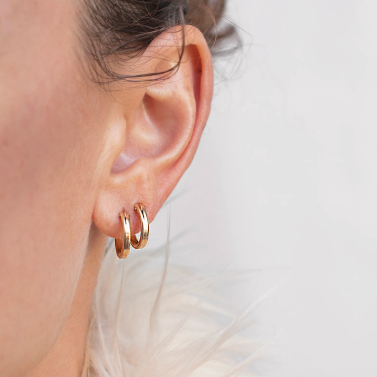 Close-up of a woman's ear featuring stacked 14k Gold Filled Zola Hoop Earrings in double piercings.