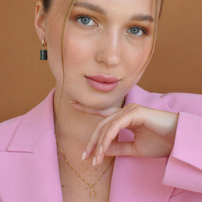 Close-up portrait of woman wearing Lykke Lucky Wishbone 14k gold filled necklace with hand near cheek in pink blazer