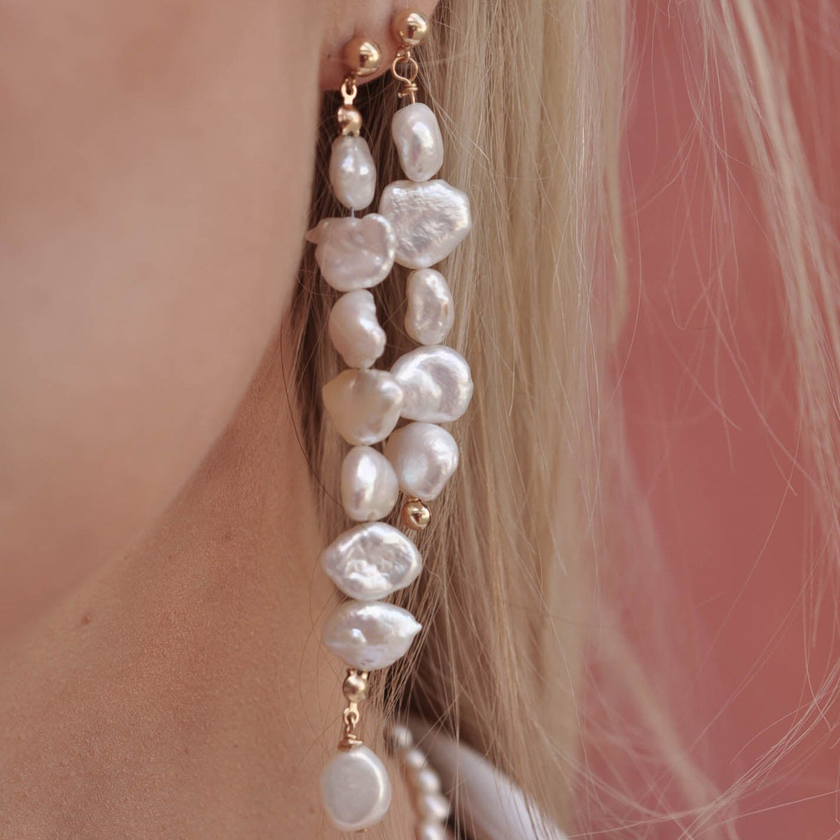 Close-up profile of a woman wearing long 14k Gold Filled stacked freshwater pearl drop earrings.