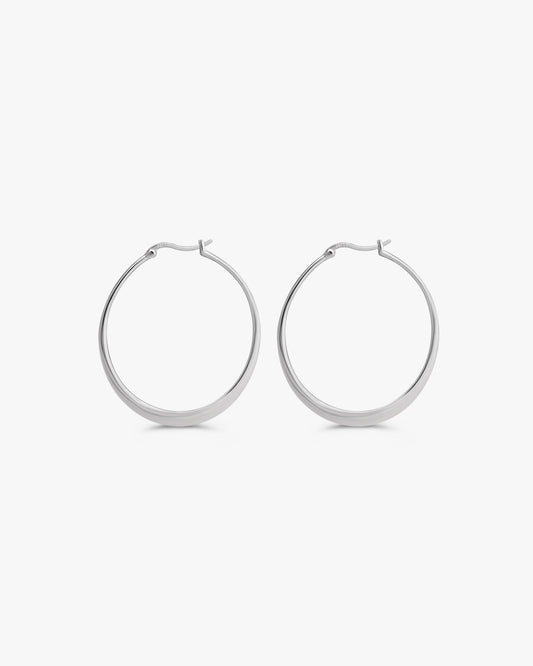 A pair of polished silver hoop earrings with a flat, wide band and secure clasp backings, shown against a clean, light gray background.