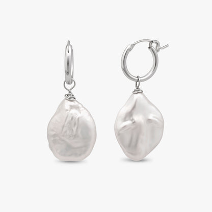 A pair of sterling silver hoop earrings with large, irregular white baroque pearl drops, shown against a light gray background.