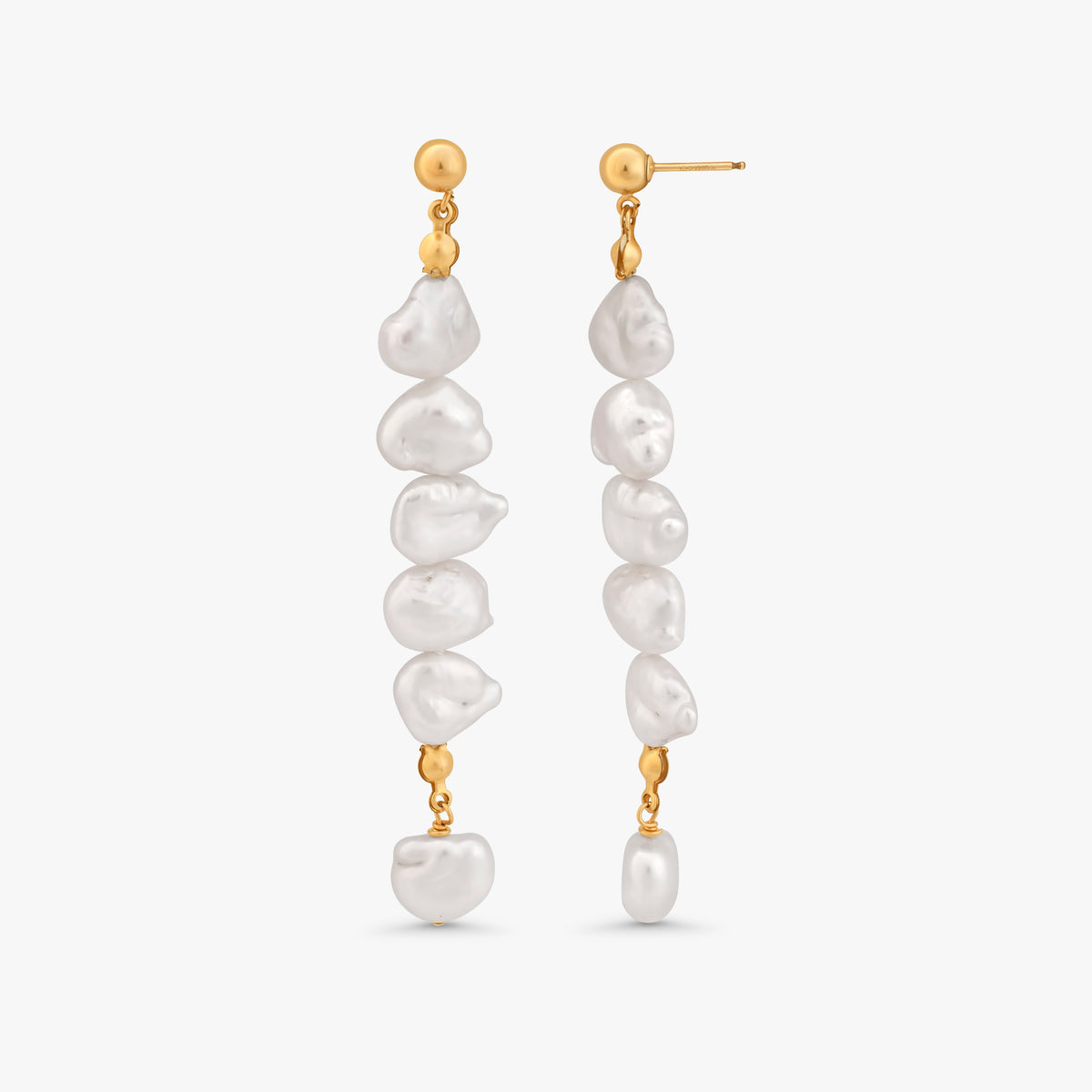 A pair of gold dangle earrings with irregular white baroque pearls, shown against a light gray background.