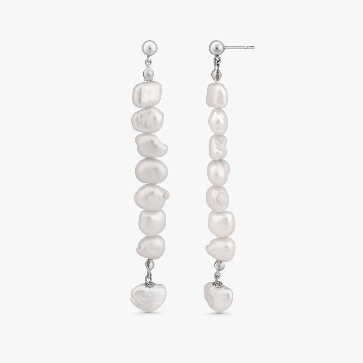 A pair of silver drop earrings featuring a vertical arrangement of irregular white baroque pearls, with a small heart-shaped pearl hanging at the bottom of each earring, shown against a light gray background.