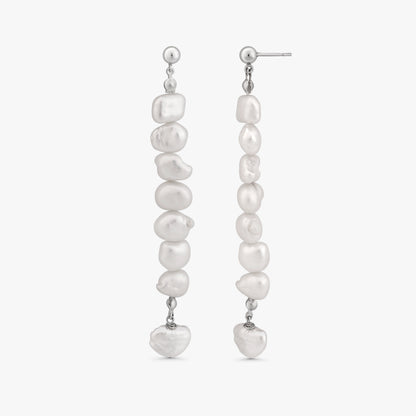 A pair of silver drop earrings featuring a vertical arrangement of irregular white baroque pearls, with a small heart-shaped pearl hanging at the bottom of each earring, shown against a light gray background.