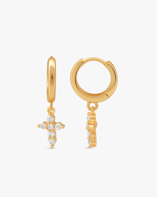 Pair of Mimi mini cross huggie hoops in 14k gold plating with crystal cross charms, on a light gray background
