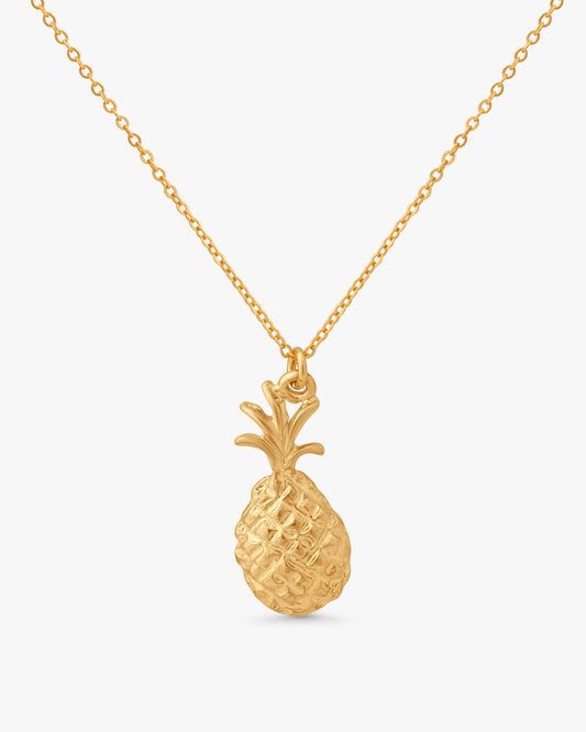 A gold pineapple pendant necklace on a delicate gold chain, presented against a clean, light gray background.