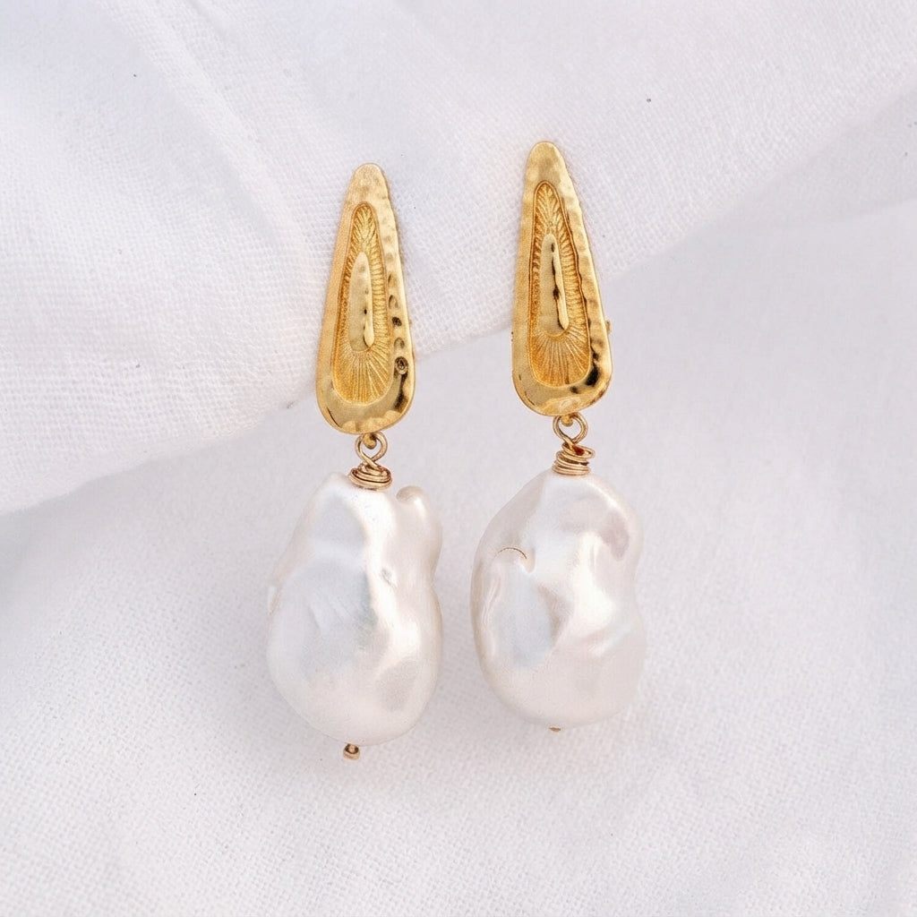 Pair of clip-on earrings featuring hammered 14K Gold Vermeil tops and hanging baroque pearls.