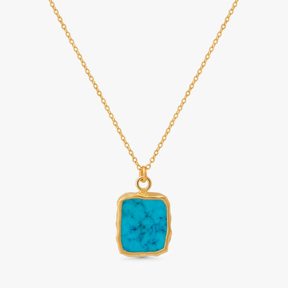 A gold chain necklace with a square pendant featuring a vibrant turquoise blue stone with natural white veining, set in a rustic gold bezel, on a light gray background.