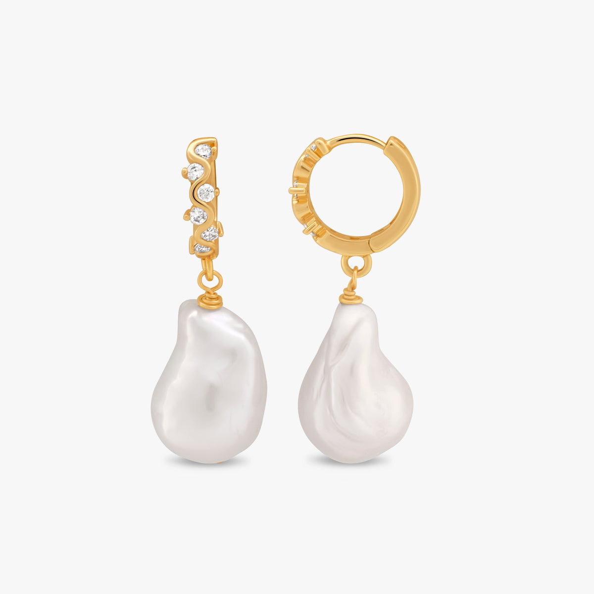 A pair of gold huggie hoop earrings with a vertical bareloeus pearl dangle and a small row of clear cubic zirconia stones, shown on a light gray background.