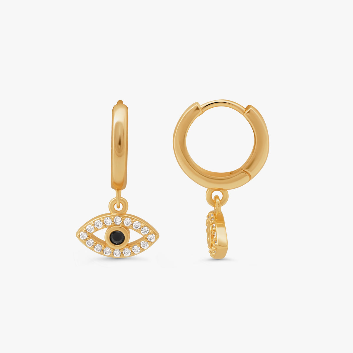 A pair of gold huggie hoop earrings with dangling evil eye charms. One earring is shown front-facing, featuring a gold eye pendant encrusted with clear crystals and a small black center.