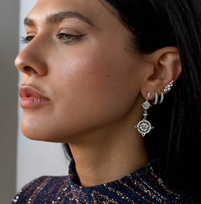 Profile view of a woman wearing Sterling Silver Freja Ear Climbers along with stacked silver hoop earrings.