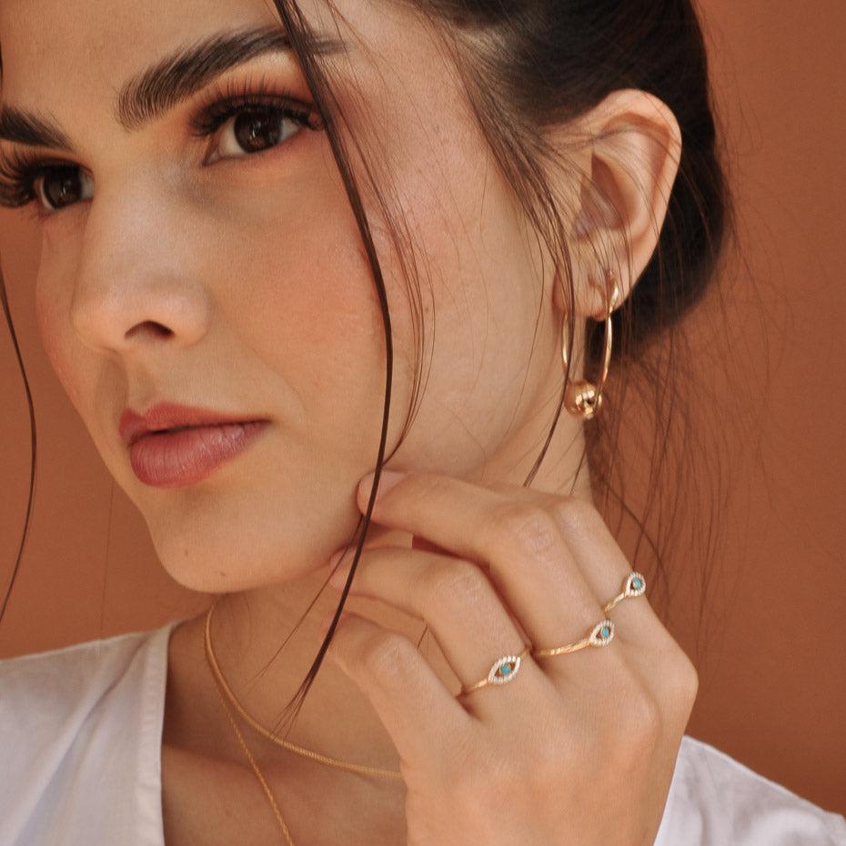 Woman wearing Celine Evil Eye 14k solid gold ring holding hand near chin