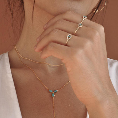 Woman wearing Celine Evil Eye 14k solid gold ring with matching necklace and ring stack