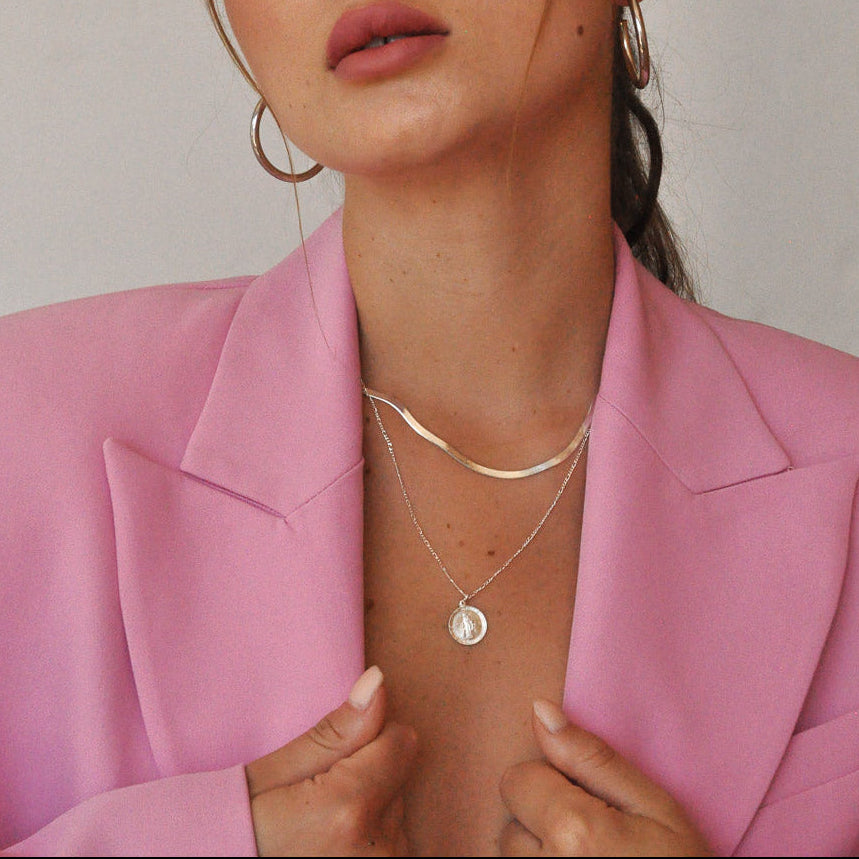 Woman wearing layered Gioia 925 sterling silver herringbone and Mary medallion necklaces