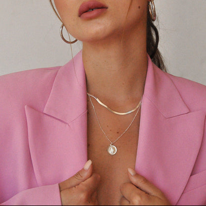 Woman wearing layered Gioia 925 sterling silver herringbone and Mary medallion necklaces