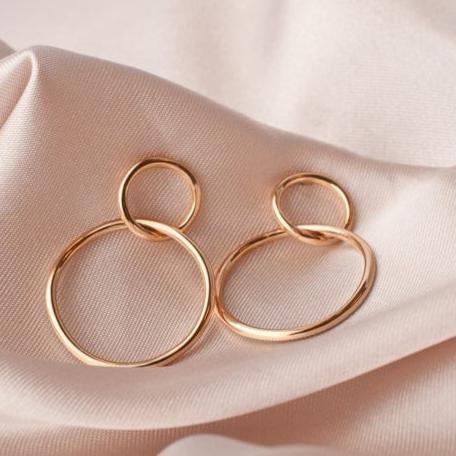 14k gold plated Sena double circle stud hoop earrings resting on soft pink fabric