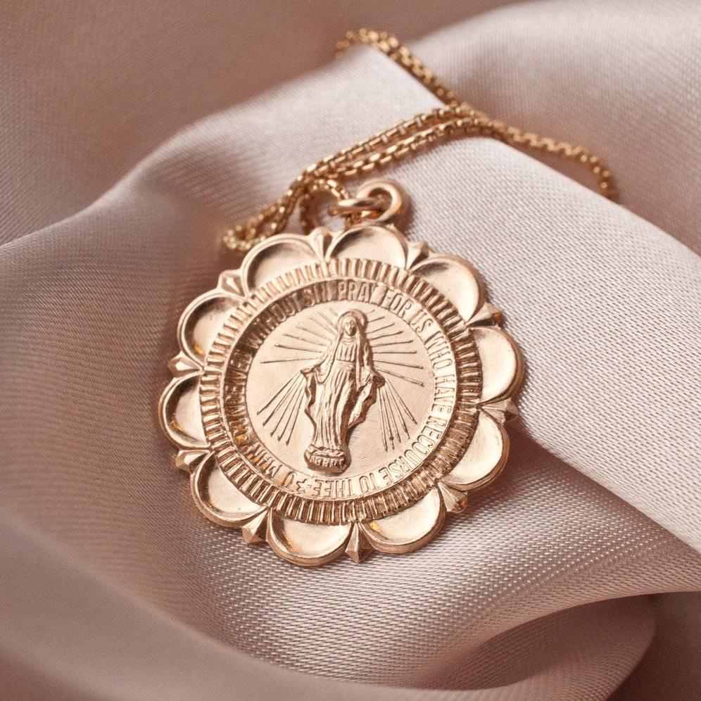 Amora Mary 14k gold filled scalloped medallion pendant necklace displayed on silk fabric