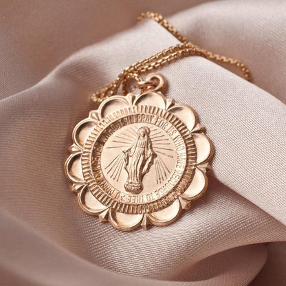 Amora Mary 14k gold filled scalloped medallion pendant necklace displayed on silk fabric
