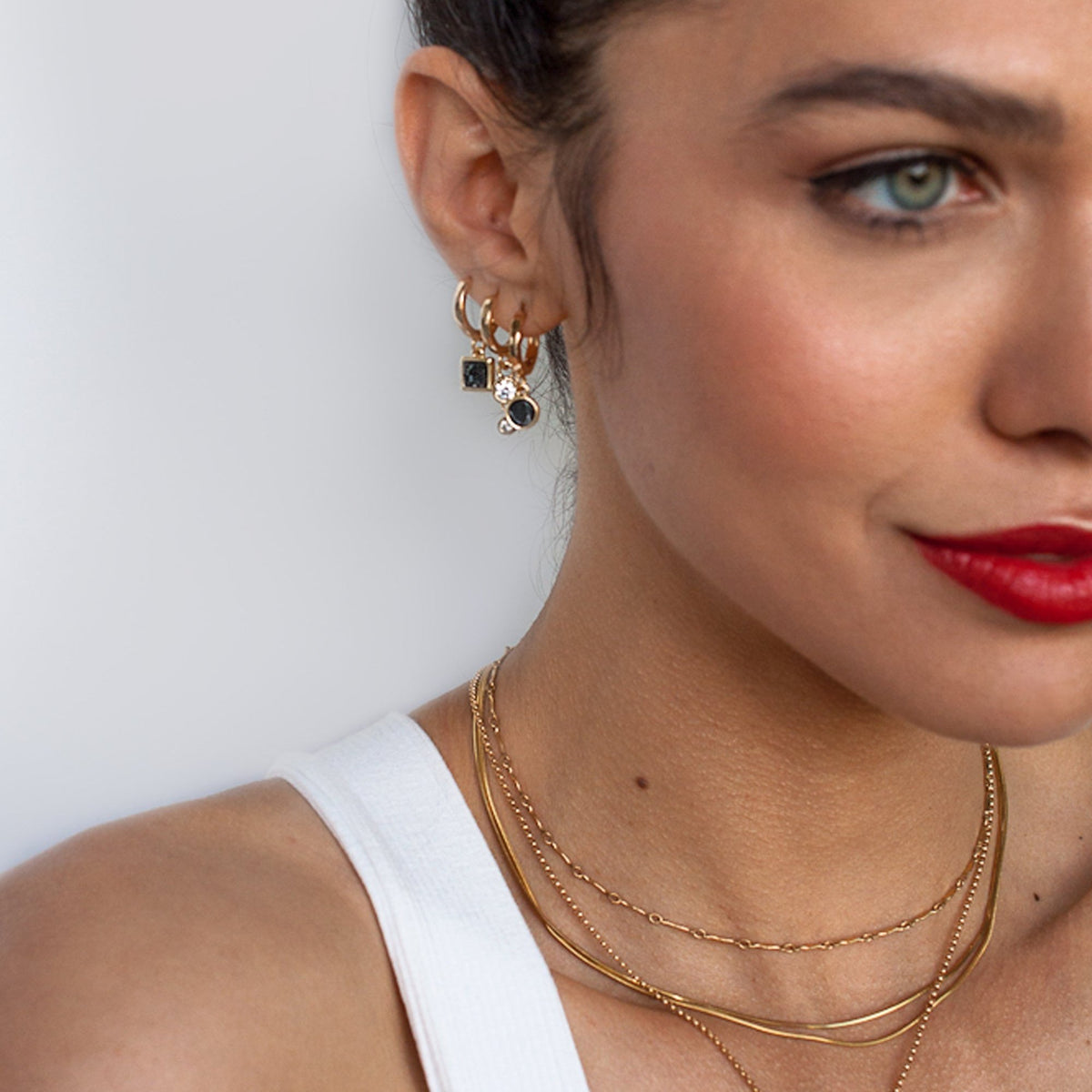 Angled portrait of woman with red lipstick wearing stacked Dagny Flat Bar 14k gold filled necklaces