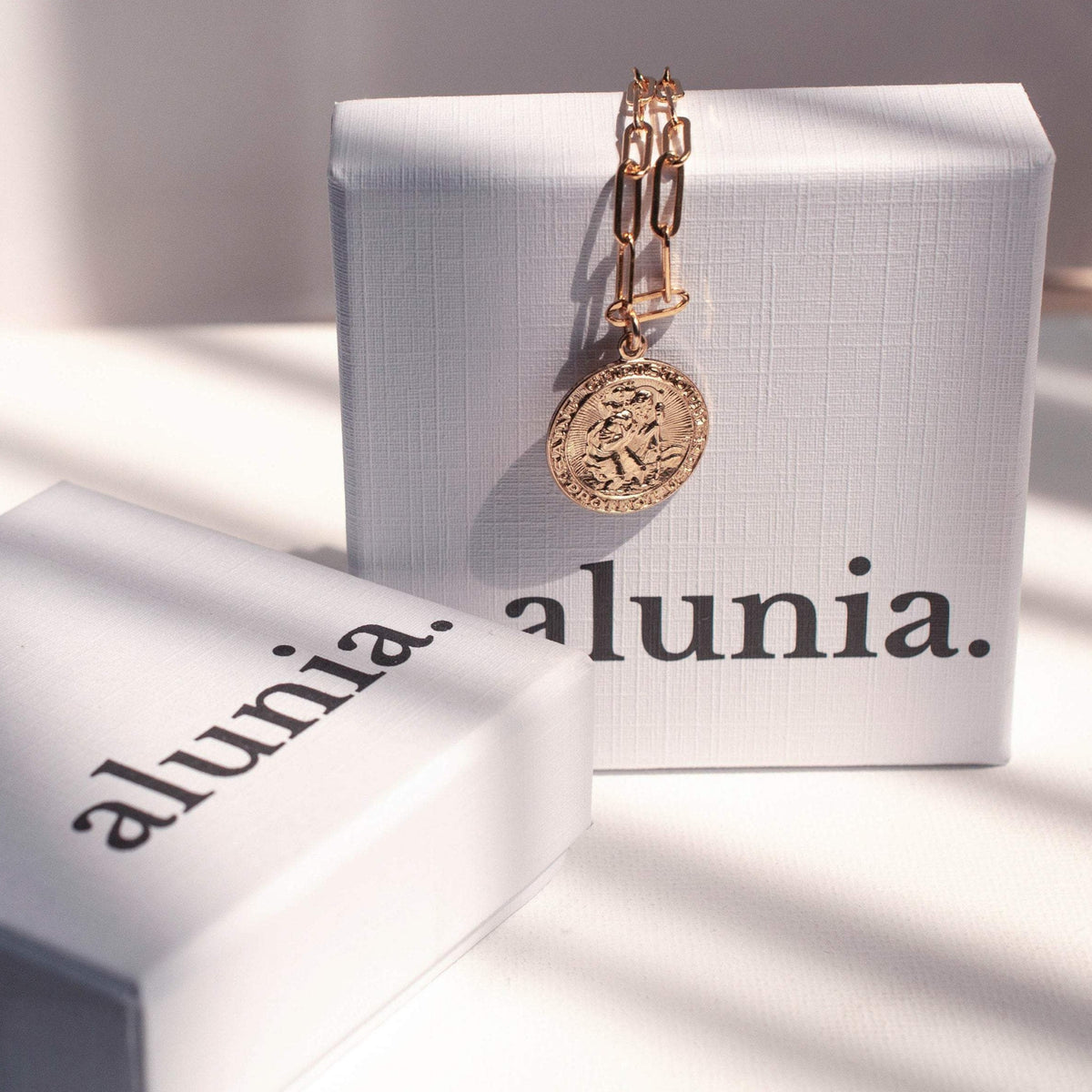 Auri Saint Christopher 14k gold filled necklace styled next to Alunia jewelry boxes