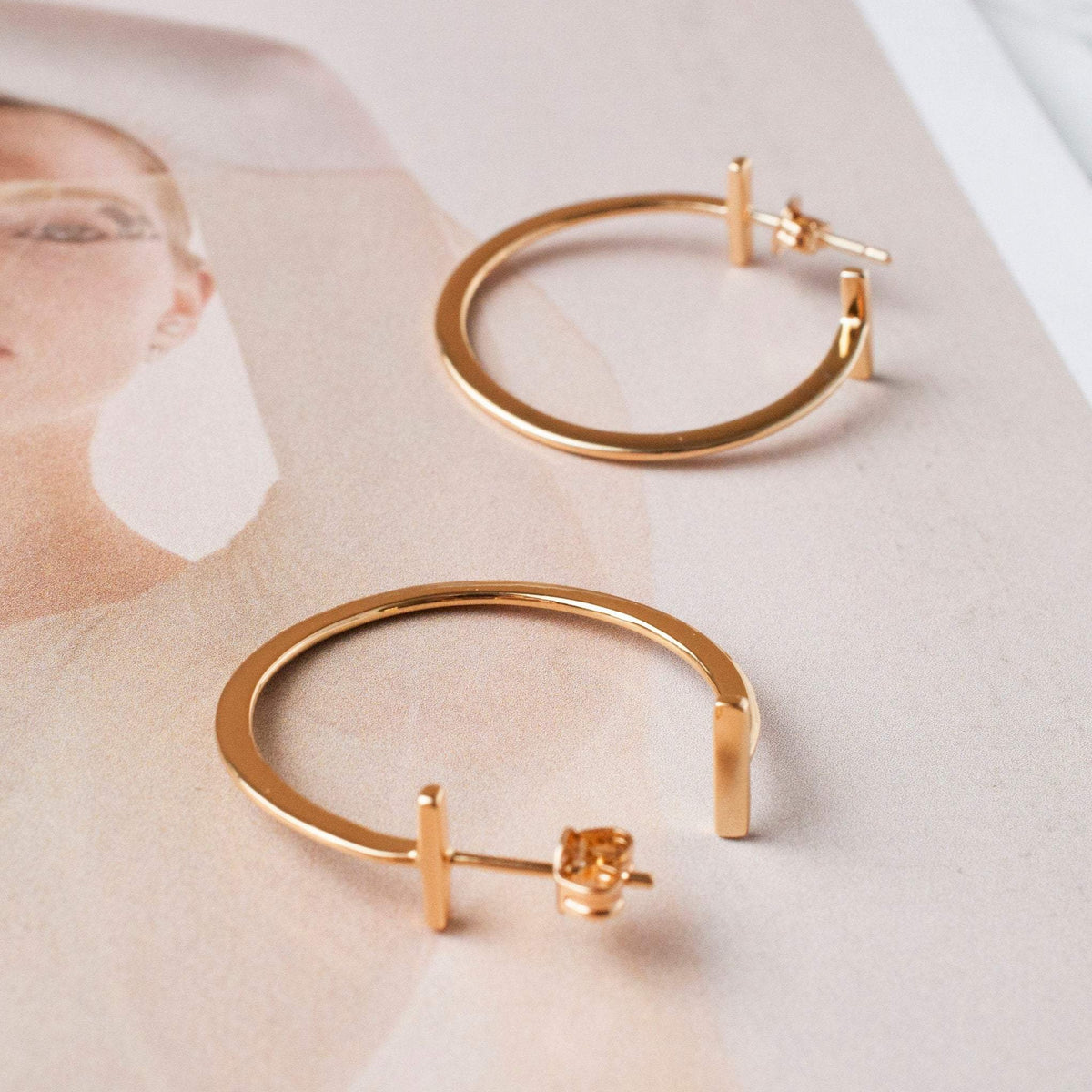 Avel Downtown Edge 14k gold plated geometric hoop earrings displayed flat on neutral surface