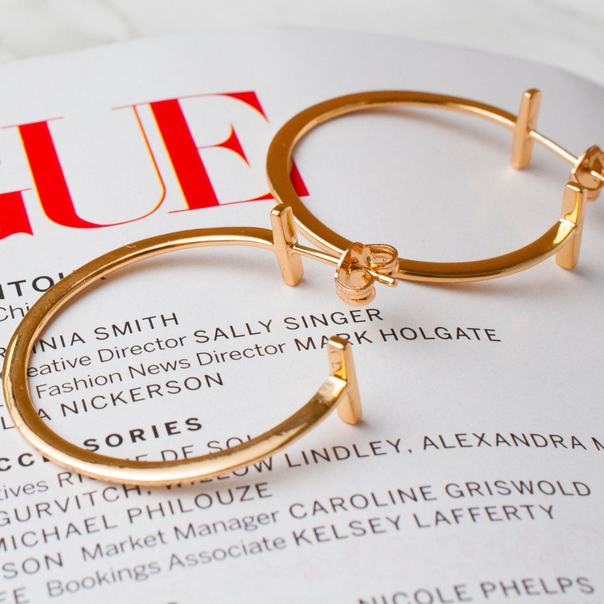 Avel Downtown Edge 14k gold plated hoop earrings styled on top of a magazine