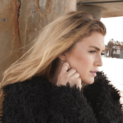 Blonde woman wearing Ora Circle Solitaire 14k gold plated stud earrings outdoors