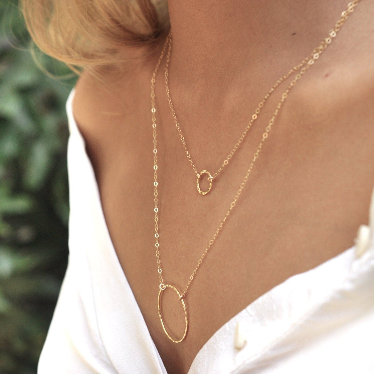 Blonde woman wearing Sora Hammered Circle 14k gold vermeil necklace layered in white unbuttoned shirt