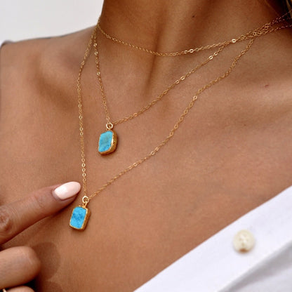 Close-up of woman adjusting Mohave Turquoise 14k gold filled necklace layered with choker chain