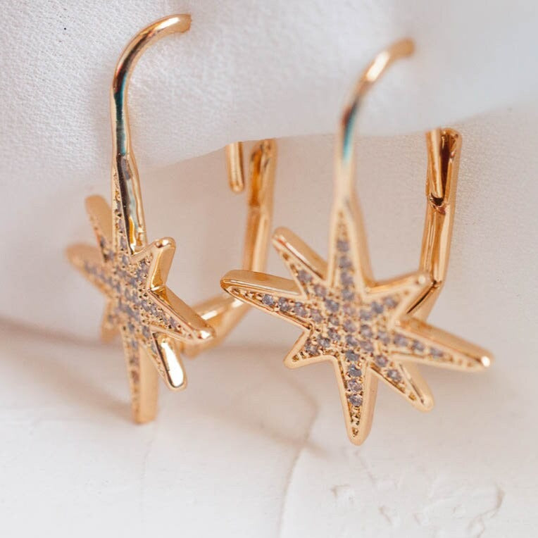 Close-up product view of women's 14k Gold Plated Sola Starburst Earrings resting upright on a smooth surface.