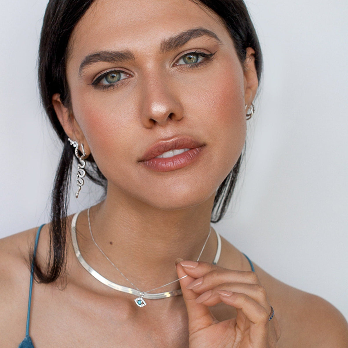 Dark-haired woman wearing Liora Evil Eye Sterling Silver necklace and snake earrings