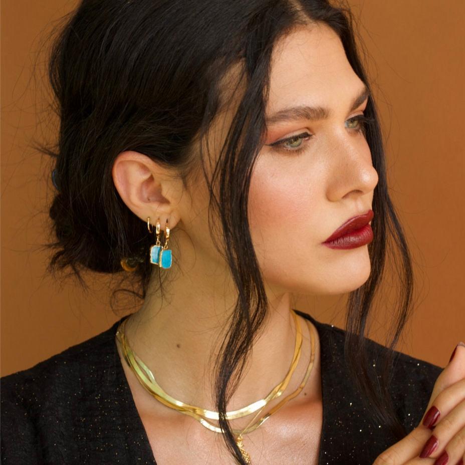 Dark-haired woman wearing Naya Herringbone Chain 14k gold vermeil necklace with turquoise earrings