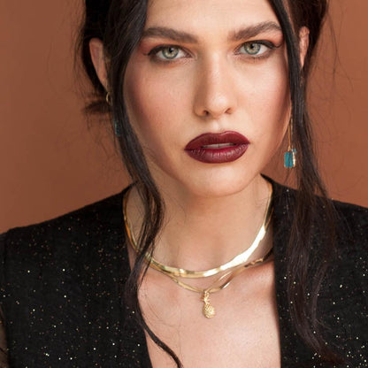 Dark-haired woman with bold lipstick wearing Copia Pineapple Goddess 14k gold filled necklace in black blazer