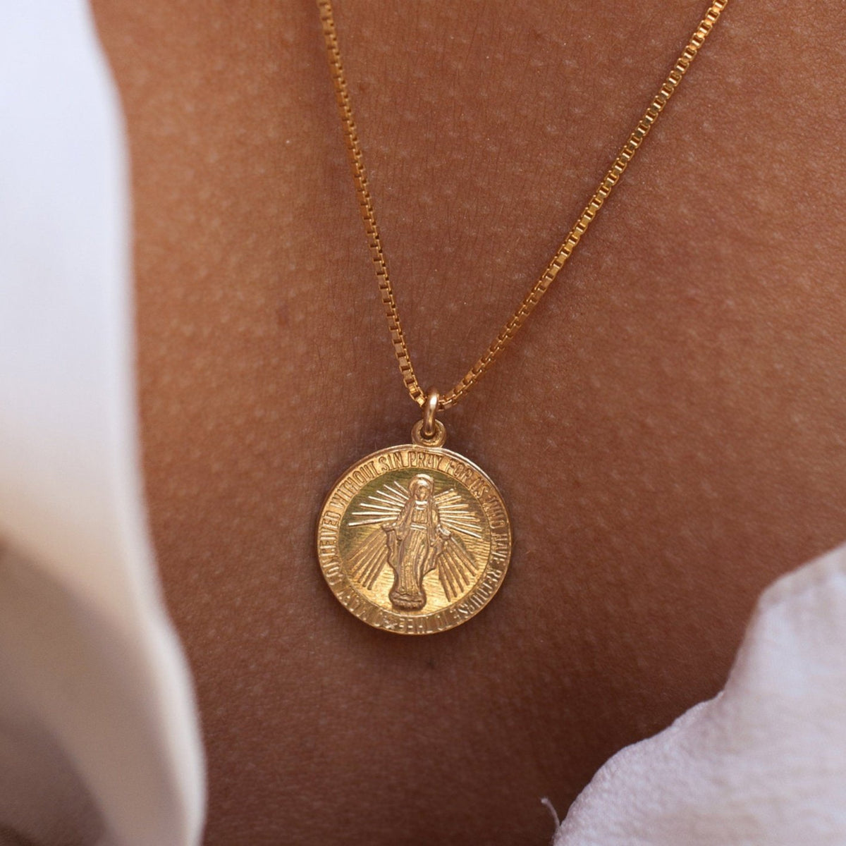 Detail shot of Annika Mary 14k gold plated Miraculous Mary coin pendant resting on woman's chest