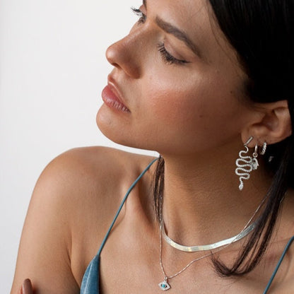 Low-angle profile view of a woman looking away while wearing Sterling Silver Vivia Snake Earrings.