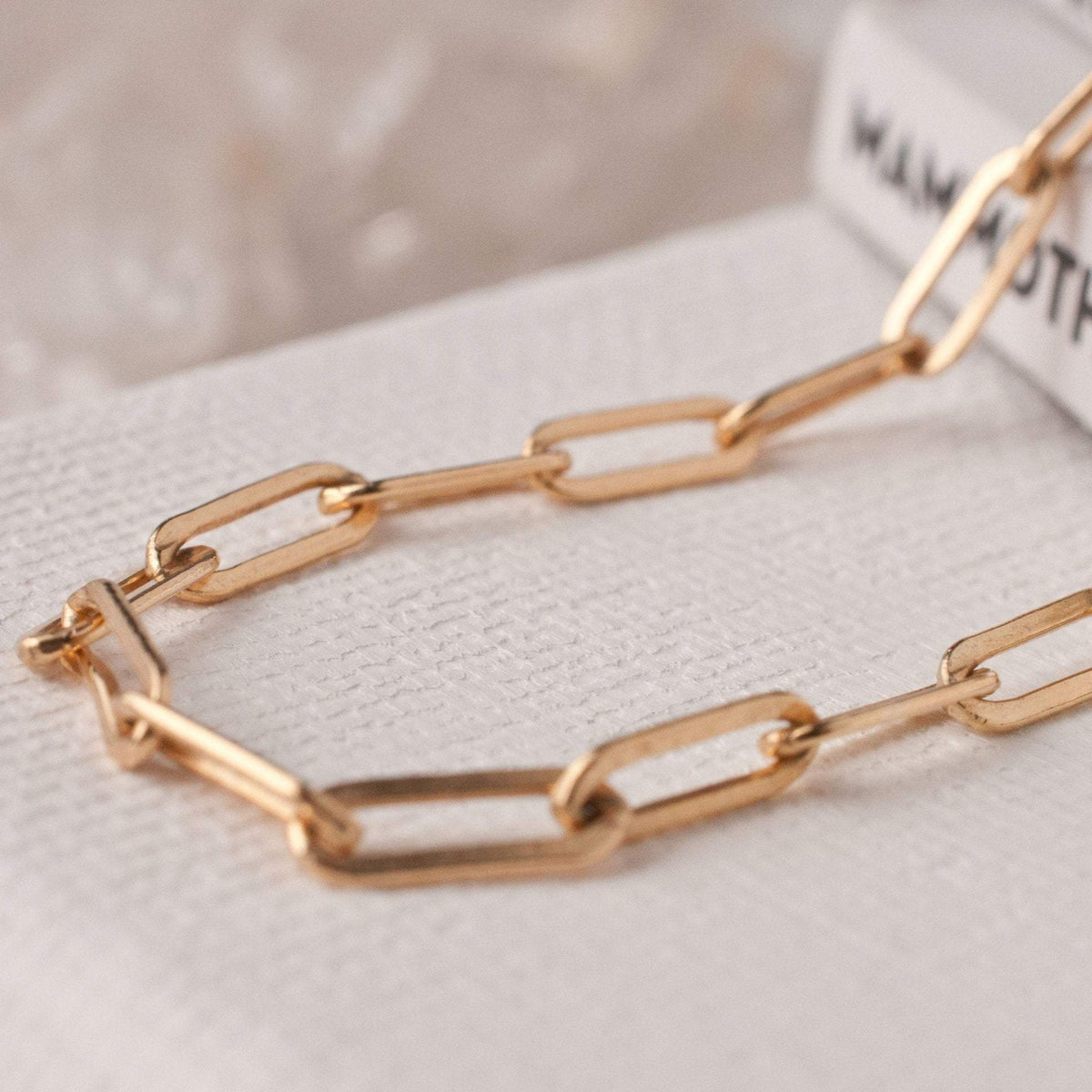 Macro detail of Embla Chunky Pearl 14k gold filled paperclip chain links on neutral background
