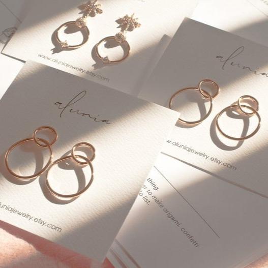 Multiple 14k gold plated Sena double circle stud hoop earrings displayed on jewelry cards