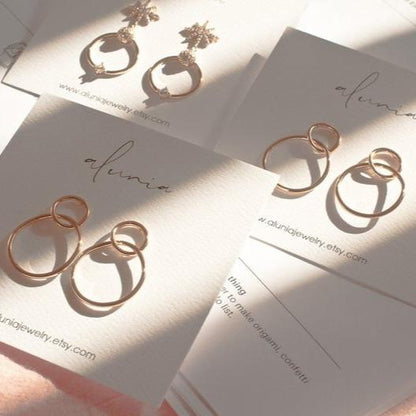 Multiple 14k gold plated Sena double circle stud hoop earrings displayed on jewelry cards