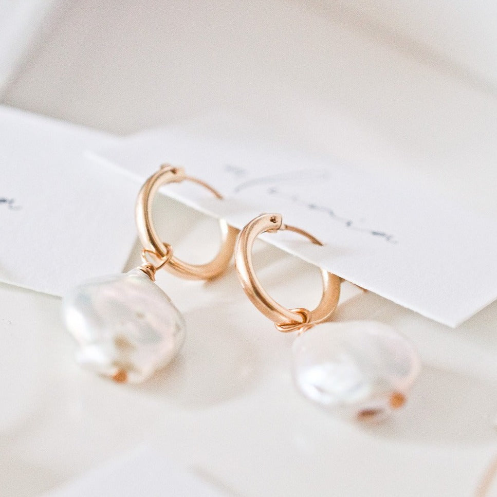 Pair of Sienna Keshi Pearl gold hoop earrings on light surface