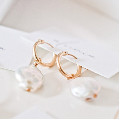 Pair of Sienna Keshi Pearl gold hoop earrings on light surface