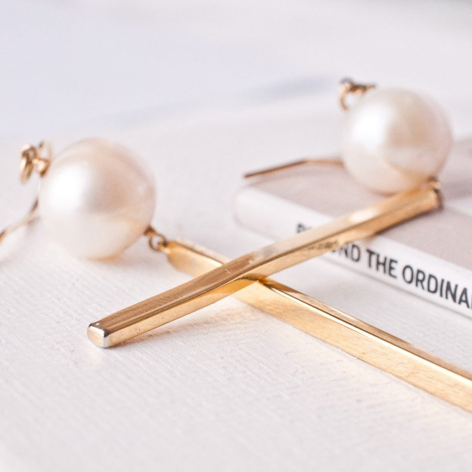 A pair of pearl bar drop earrings with gold-filled French hooks and polished bars, displayed on a white surface.