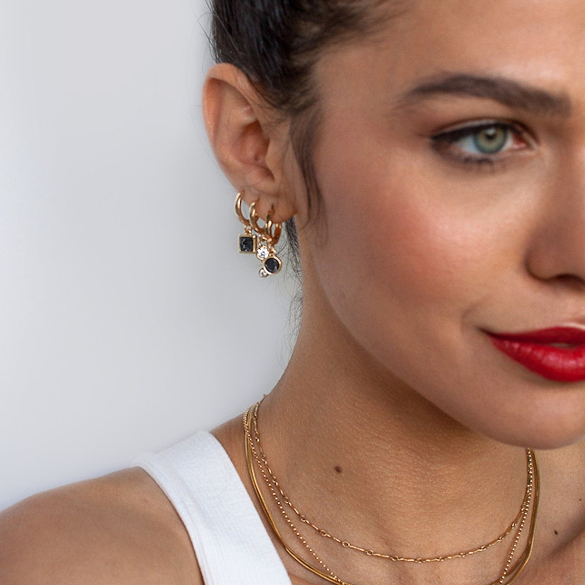 Portrait of a woman with red lipstick wearing 14k Gold Plated Ziva Druzy Hoop Earrings and layered gold chains.