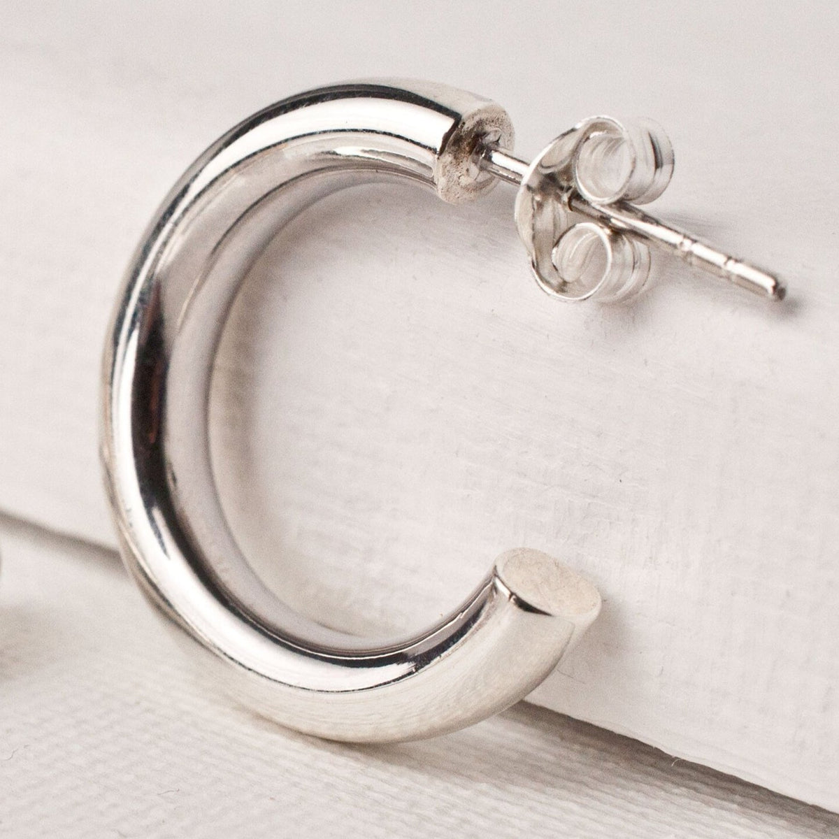 Single women's sterling silver chunky open hoop earring showing butterfly post back.