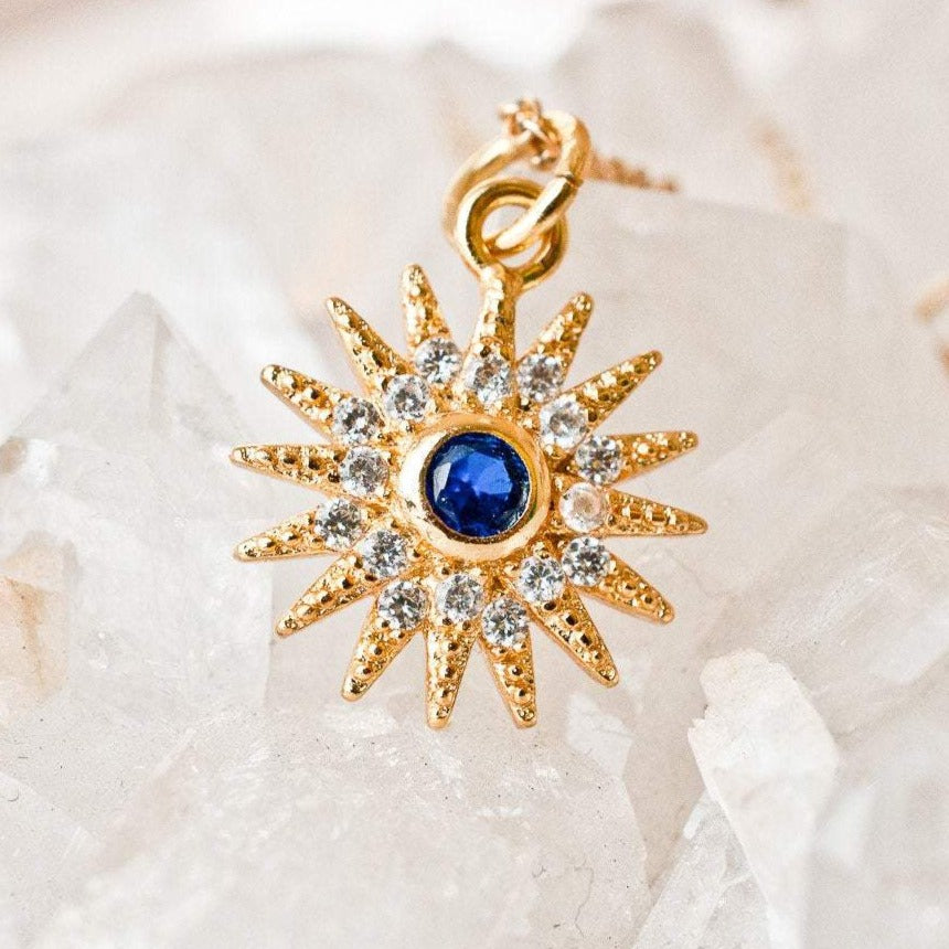 Sunniva Sun Ray & Starburst 14k gold filled pendant displayed on raw white crystal cluster