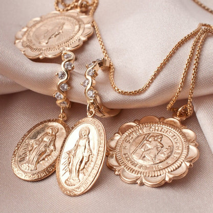 Viva Saint Christopher 14k gold filled scalloped medallion displayed alongside other gold religious charms