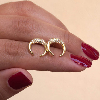 Woman holding pair of Bravi Double Horn 14k gold plated stud earrings between fingers