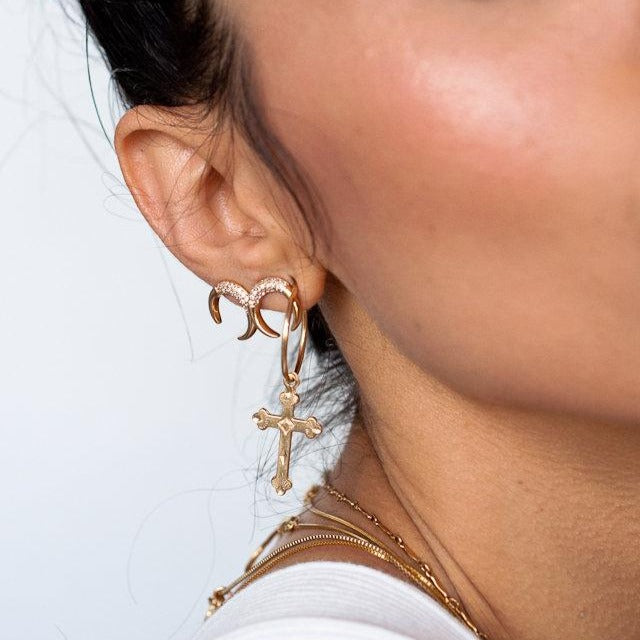 Woman wearing 14k gold filled Haven cross charm hoop earrings